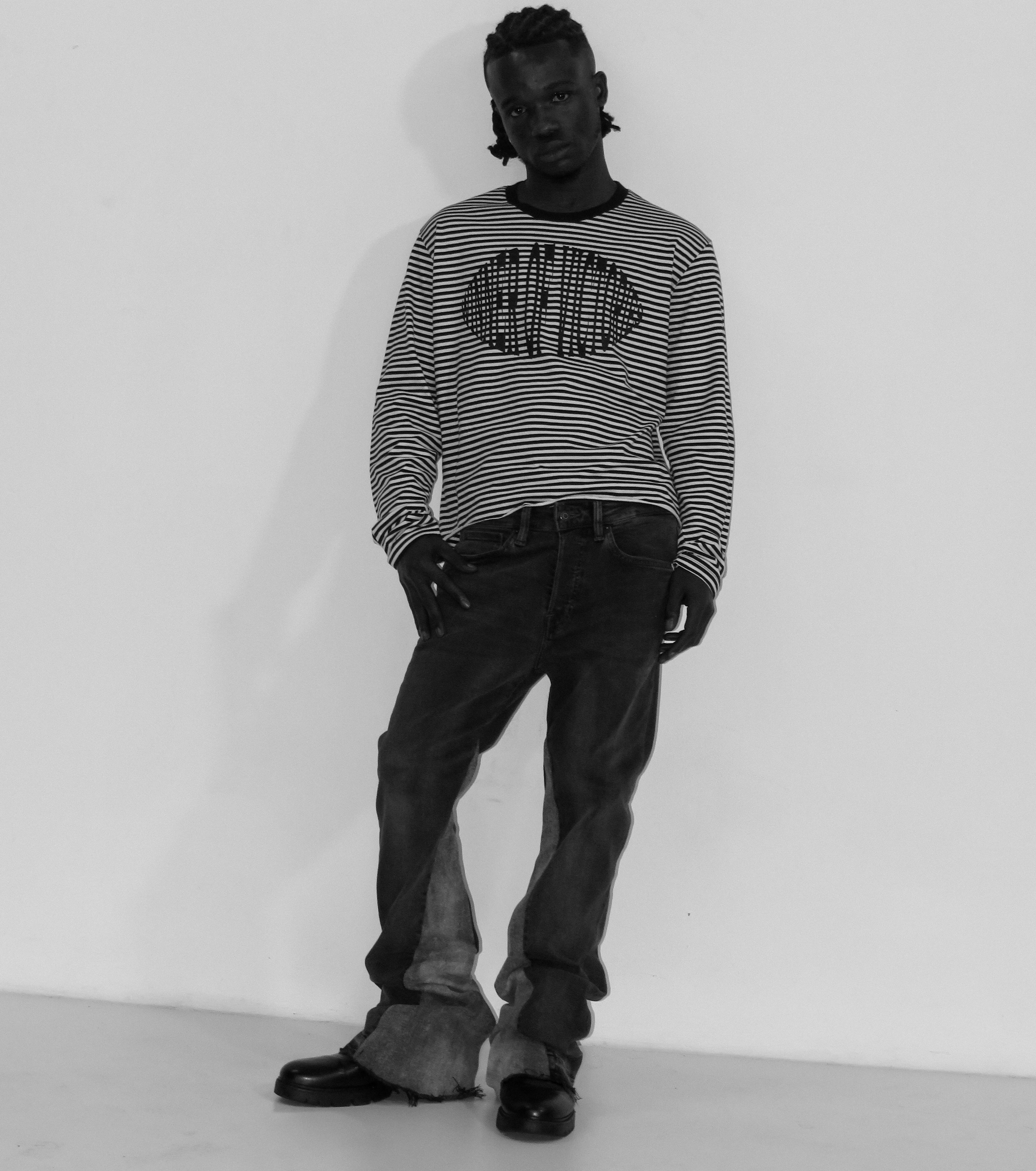 Person wearing a striped sweater and dark pants on a white background