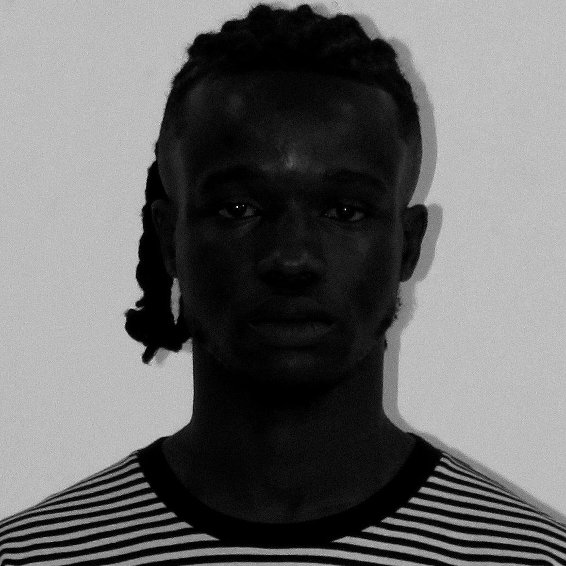 Black and white portrait of a person with braided hair wearing a striped shirt.