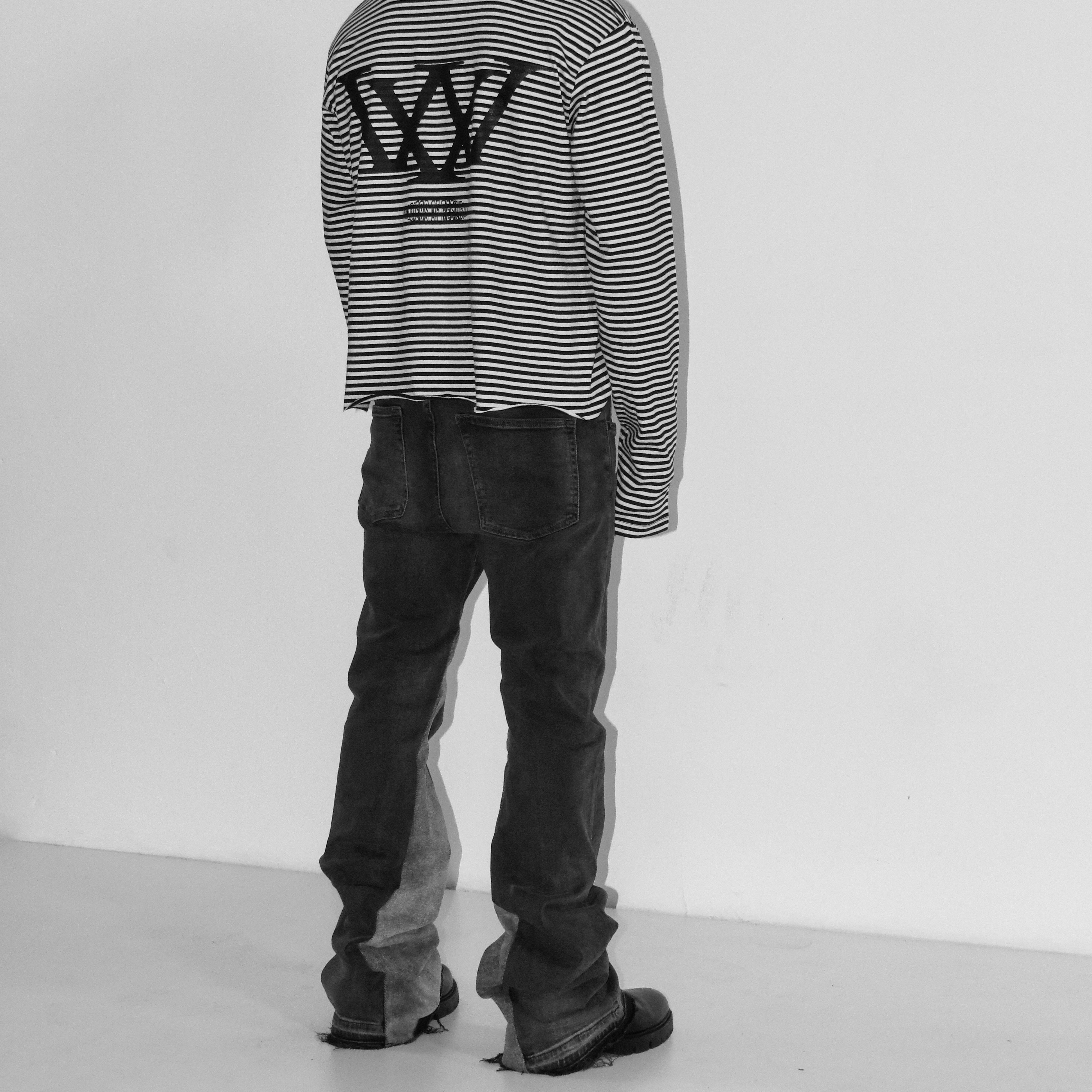 Person wearing a black and white striped sweater with a logo on the back, standing against a plain background.