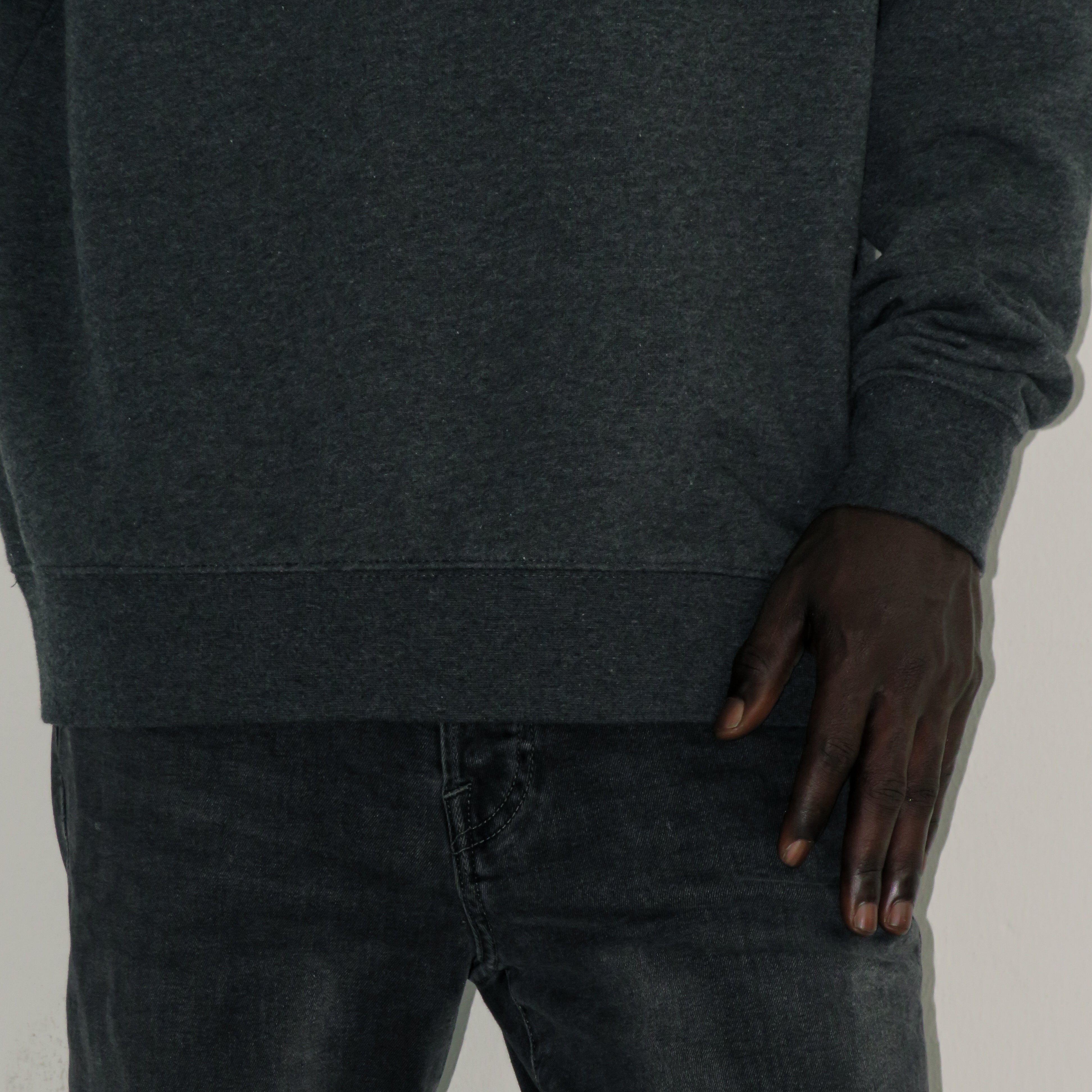 Person wearing a dark gray hoodie and jeans with a neutral background
