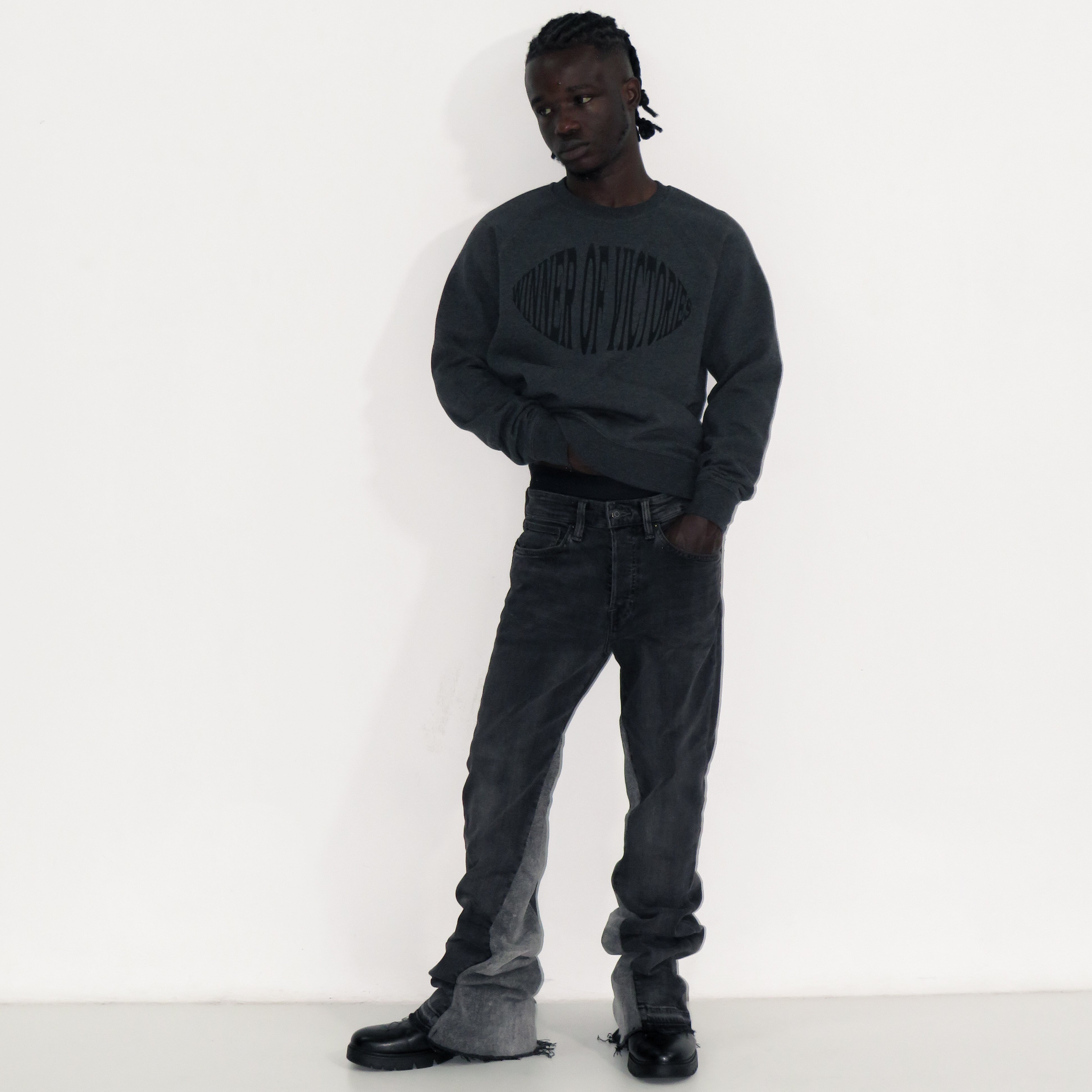 Person wearing a dark gray sweatshirt and jeans against a white background