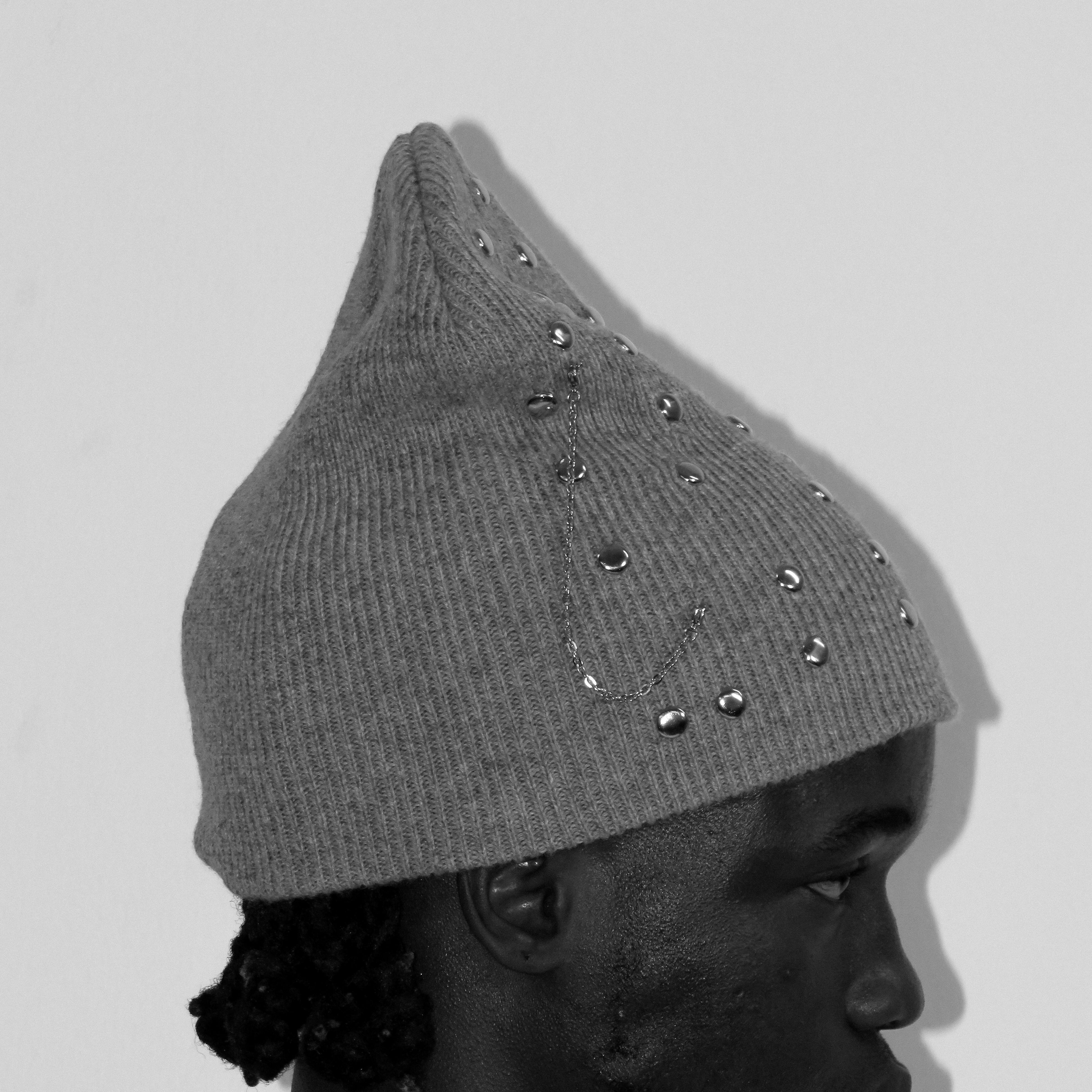 Gray knit beanie with decorative studs on a plain background