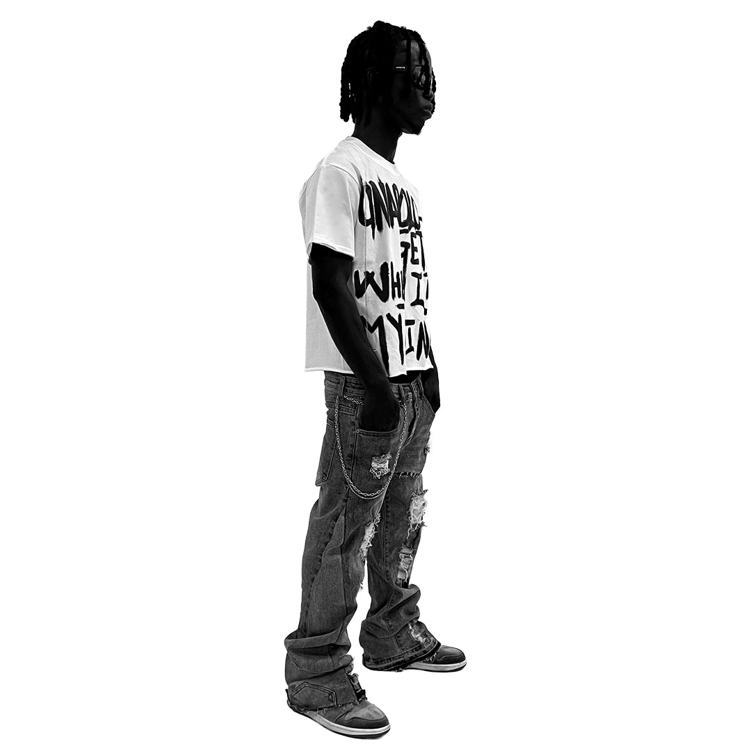 Person wearing a white t-shirt with text and dark jeans on a white background